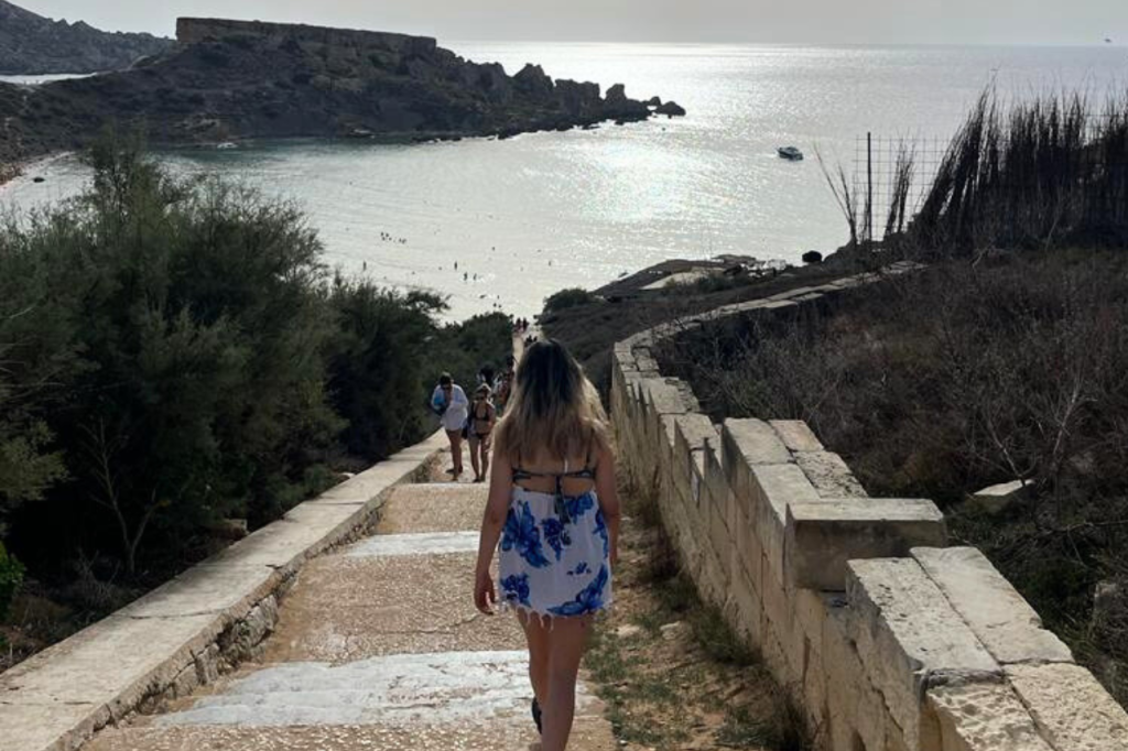 Mujer bajando escalera hacia playa